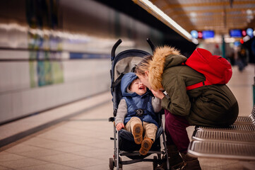 Joyful Interaction at Metro Station. Young mother and laughing toddler enjoy a playful moment while...