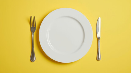 Top down view of a white plate isolated on yellow background with fork and knife with copy space