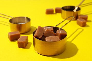 Cubes of salted caramel with salt on a yellow background