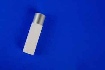 Plastic white tube for cream or lotion. Skin care or sunscreen cosmetic on blue background 