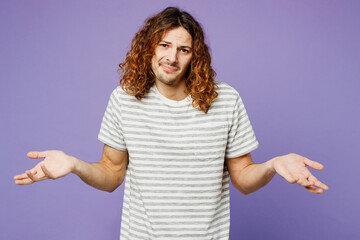 Young doubtful sad man he wear grey striped t-shirt casual clothes spread hands shrugging shoulders...