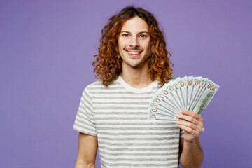 Young happy rich man he wear grey striped t-shirt casual clothes hold in hand fan of cash money in...