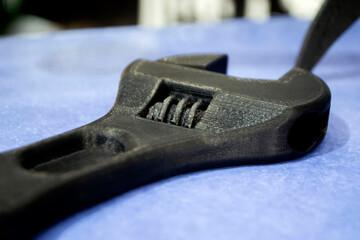 Model prototype of an adjustable wrench from of black plastic printed on a 3D printer. Concept 3D...