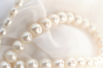 The gentle curve of a pearl string on a white cloth evokes a sense of serene elegance. It's a...