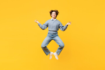 Fototapeta na wymiar Full body young woman wear grey knitted sweater shirt casual clothes jump high hold spreading hands in yoga om aum gesture relax meditate try to calm down levitate isolated on plain yellow background