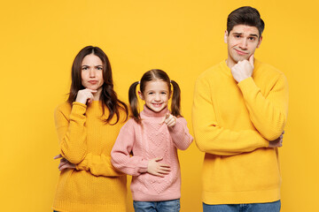 Young minded pensive parents mom dad with child kid girl 7-8 years old wear pink knitted sweater casual clothes point index finger camera on you isolated on plain yellow background Family day concept