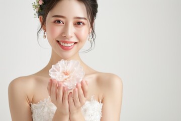 お花を持つウェディングドレス姿の笑顔の日本人女性（前撮り・結婚式・ウェディングフォト）