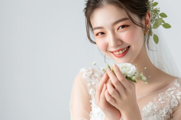 お花を持つウェディングドレス姿の笑顔の日本人女性（前撮り・結婚式・ウェディングフォト）