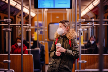 Masked Woman with Coffee in Train. Young woman with mask holding coffee cup in train