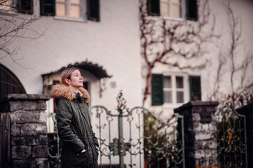 Young Woman Admiring Suburban House. A young woman in a winter coat admiring a house