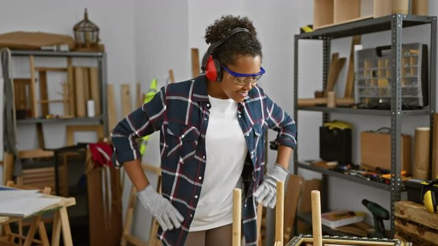 Smiling woman in safety gear assembles furniture in a workshop