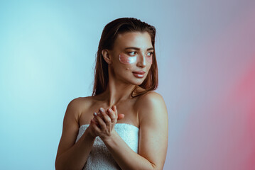 A portrait of a young girl with patches under her eyes and a towel on her head. Beauty treatments, cosmetology