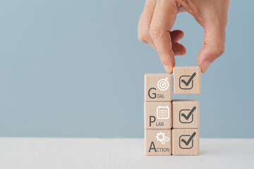 Hand arranged Wooden cube block with Goal, Plan, Action text and icon. Business goals for planning...