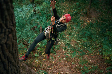 Naklejka premium Focused on the climbing up. Woman is in the forest, using the safety equipment