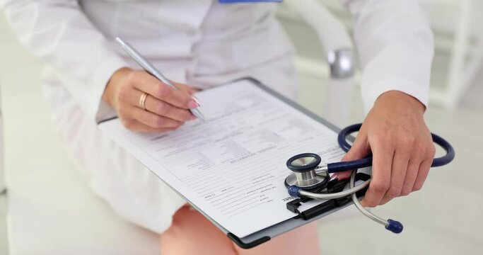 Hands of a doctor filling out written medical documents in clinic