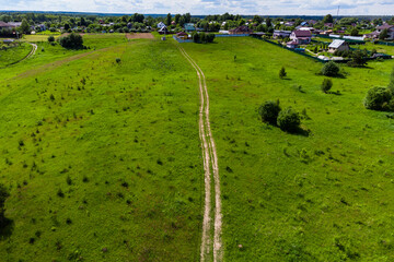Aerial view of a dirt country road leading towards rural development