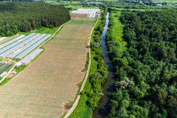 Field with crops located on the river bank, aerial view