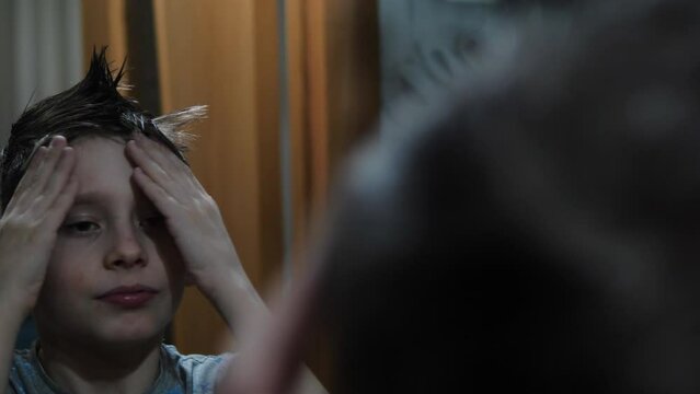 happy european boy 9 years old styling his hair using hair products. hair care . boy in front of the mirror creates a fashionable hairstyle.