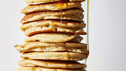 A stack of pancakes with a flat head and short large head is being drizzled with syrup.