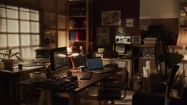 No people lowkey shot of 90s style room interior with dimmed light and lots of vintage tech devices as old computer monitors, speakers and recorders