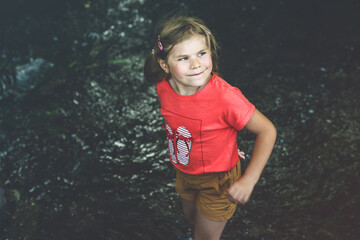A Happy Girl Embraces the Joys of Childhood as She Explores a Summer Creek, Immersing Herself in...