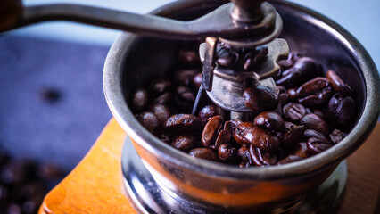 Roasted black and brown coffee beans in a manual coffee grinder.