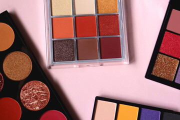 Various colorful eyeshadow palettes on bright pink background. Flat lay.