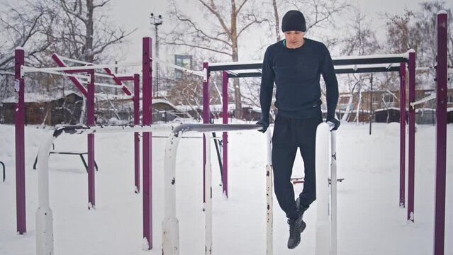Slim sportsman do arm exercise outdoor gym. Guy training dip push up bar. Work out outside snowy day. Man fit train sport park. Cold winter fitness workout. Burn body fat hiit. Male person health care