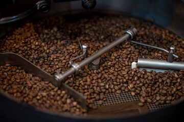 Close up of Coffee beans during the roasting process, moving paddle of the screening hopper cooling the coffee beans after roasting. Drum type roaster