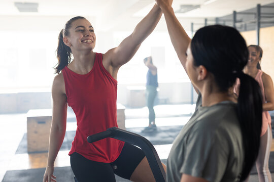 Caucasian female friends giving high-five after exercising in health club, copy space