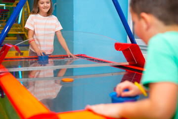 Boy and girl friends play air hockey together in a children's entertainment center	 - 725397794