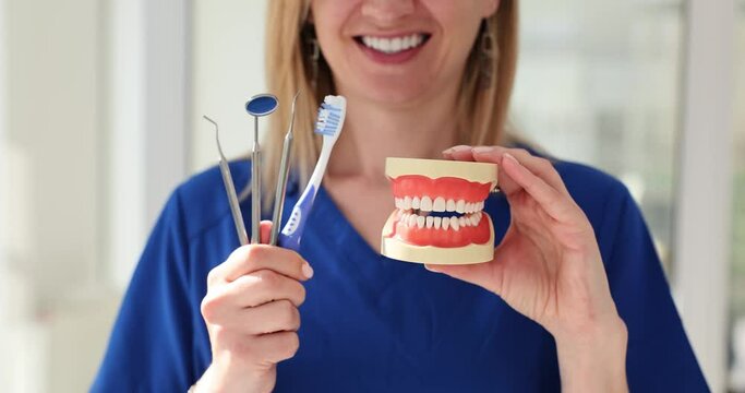 Model of dentures and dental instruments in hands of dentist