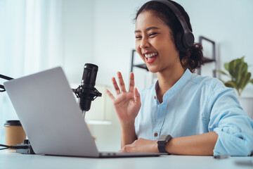 Cheerful beautiful Asian woman wearing headphones with looking and talk to camera at video calling...