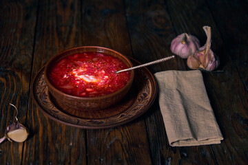 National Ukrainian borscht, earthenware, borscht with sour cream in a plate, garlic, napkin and...