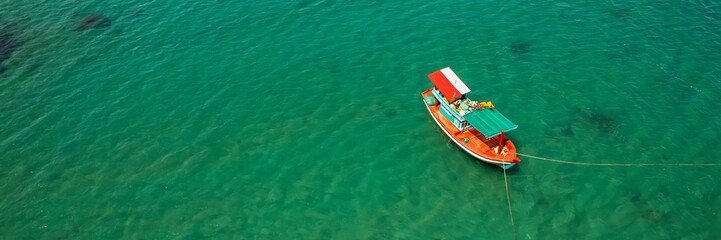 Fototapeta na wymiar Aerial view of a traditional wooden boat floating on clear turquoise waters, symbolizing travel or fishing concepts