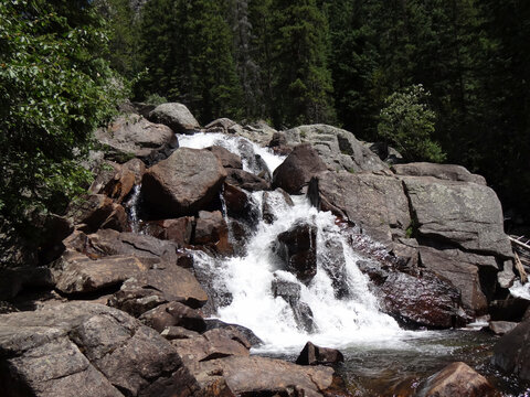 Waterfall cascading over a rocky cliff in front of lush forest in Granby.