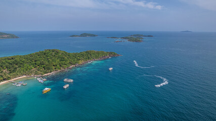 Aerial view of tropical islands with turquoise waters, tour boats, and trailing wake patterns, capturing a serene vacation destination