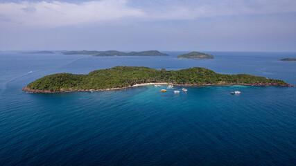 Aerial view of a tranquil tropical island with boats near the shore, epitomizing a serene vacation getaway