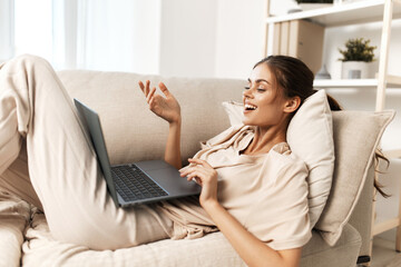 Smiling woman working on laptop in cozy living room, surrounded by modern technology and...