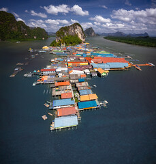 Mesmerizing aerial shot of Koh Panyee, Thailand's floating village. Vibrant stilted structures rise above the turquoise waters, capturing the essence of a unique and captivating way of life