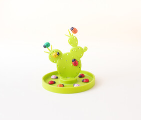 Green cactus with red, green, orange, blue, yellow and pink ladybugs with black dots on a white background. Spring concept. Flat lay.