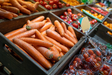 Carrots in a wooden box in the fruit and vegetable section of a grocery supermarket. Sale of carrots, selective focus. Vegetables in a supermarket close-up