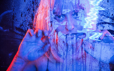 Cold blue color. With hands on the wet transparent plastic sheet. Stylish woman with white hair