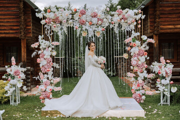 portrait of a beautiful young bride in a white dress with a long train with a long veil and a...