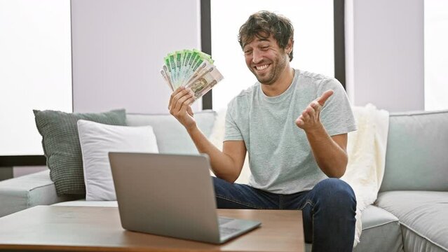 Excited young man, laptop aglow, joyfully celebrates business win at home, waving russian rubles with a winner's smile in a triumphant achievement