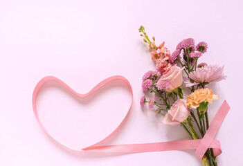 Bouquet of fresh flowers with roses, carnations and chrysanthemums with pink heart-shaped ribbon and empty space for text. Romantic gift for Valentine's Day, March 8, Mother's Day or Birthday