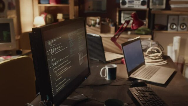 No people shot of programming codes appearing on black desktop computer monitor in 80s style room stacked with vintage tech devices and gadgets