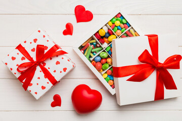 Valentine day composition: sweet candy, with gift boxes with bow and red felt hearts, photo...