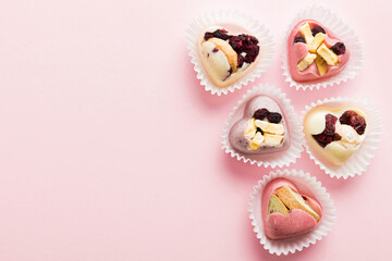 chocolate sweets in the form of a heart with fruits and nuts on a colored background. top view with space for text, holiday concept