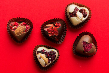 chocolate sweets in the form of a heart with fruits and nuts on a colored background. top view with space for text, holiday concept